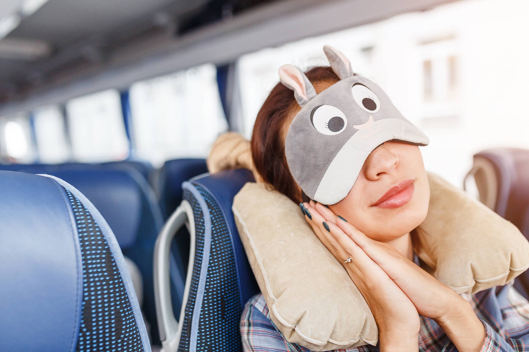 Woman sleeping in a bus with eye mask and neck pillow