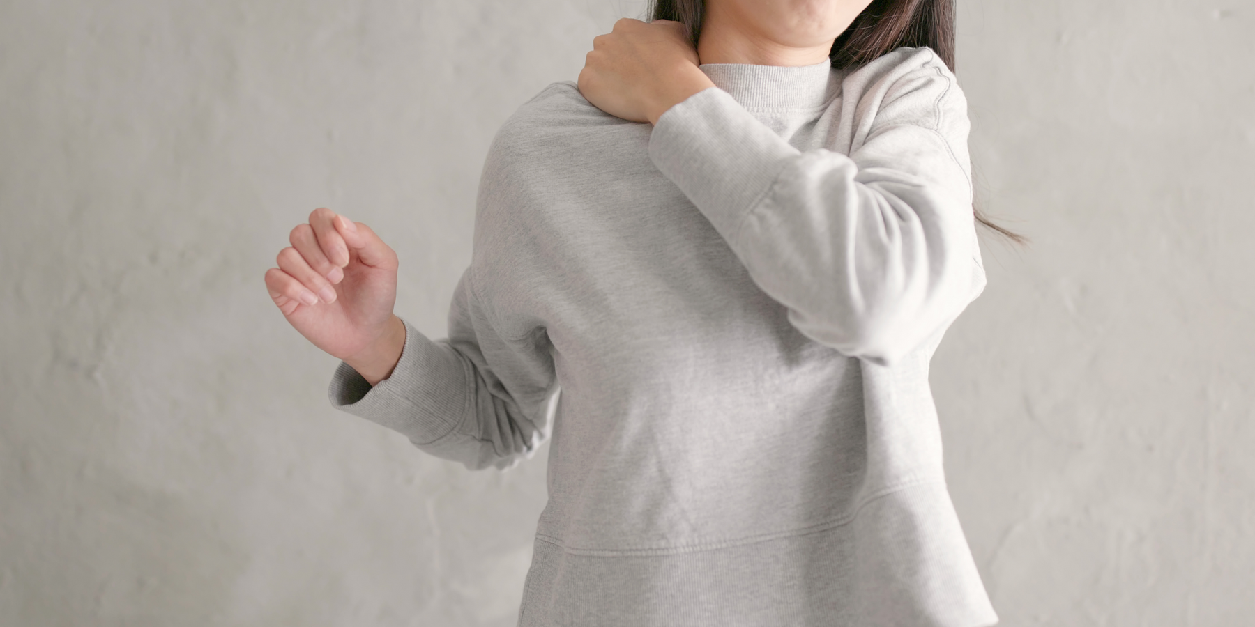 Woman massaging her right shoulder with her left hand