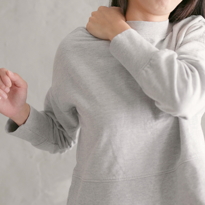 Woman massaging her right shoulder with her left hand